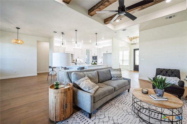 living room with beamed ceiling, ceiling fan, and light hardwood / wood-style floors