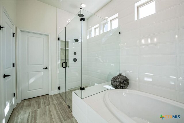 bathroom with independent shower and bath and hardwood / wood-style flooring