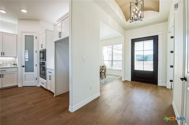 foyer entrance featuring dark hardwood / wood-style flooring and a notable chandelier