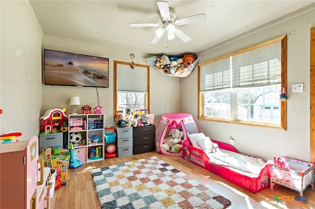 game room with wood finished floors, a wealth of natural light, and a ceiling fan