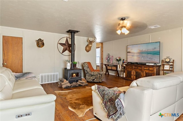 living area featuring a wood stove, visible vents, and wood finished floors