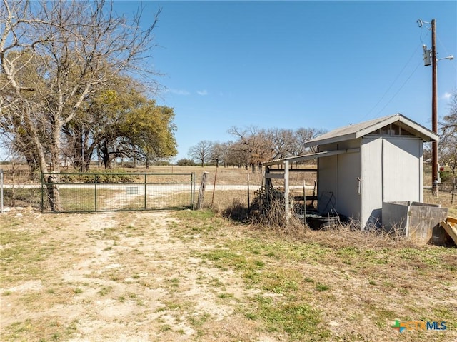 view of yard featuring an outbuilding, a gate, and fence