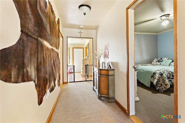 corridor featuring light carpet, crown molding, and baseboards