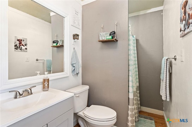 bathroom featuring toilet, a shower with shower curtain, wood finished floors, vanity, and baseboards