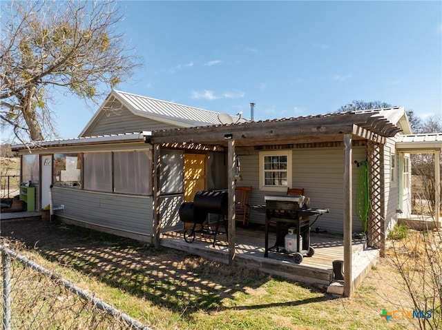 back of house featuring a sunroom, metal roof, a deck, and a pergola