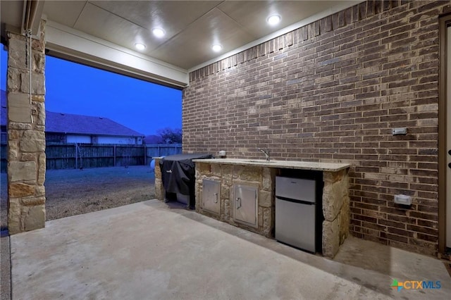 view of patio with a sink, grilling area, an outdoor kitchen, and fence