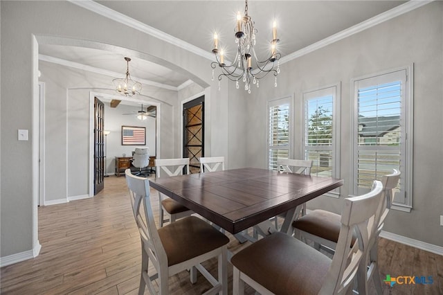 dining space with baseboards, arched walkways, light wood-style floors, and ornamental molding