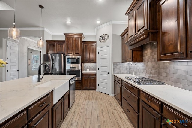 kitchen featuring light wood-style flooring, arched walkways, dark brown cabinets, appliances with stainless steel finishes, and pendant lighting