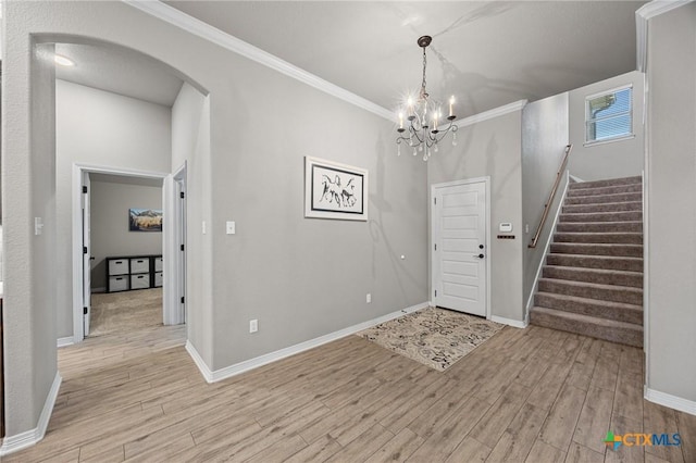 entrance foyer with light wood finished floors, baseboards, stairway, ornamental molding, and arched walkways