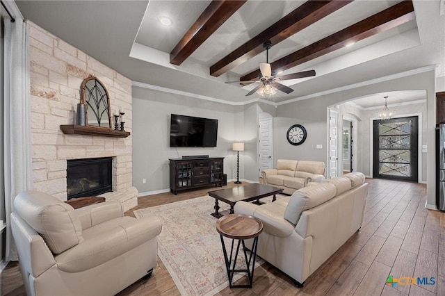 living area with a stone fireplace, beamed ceiling, wood finished floors, and arched walkways