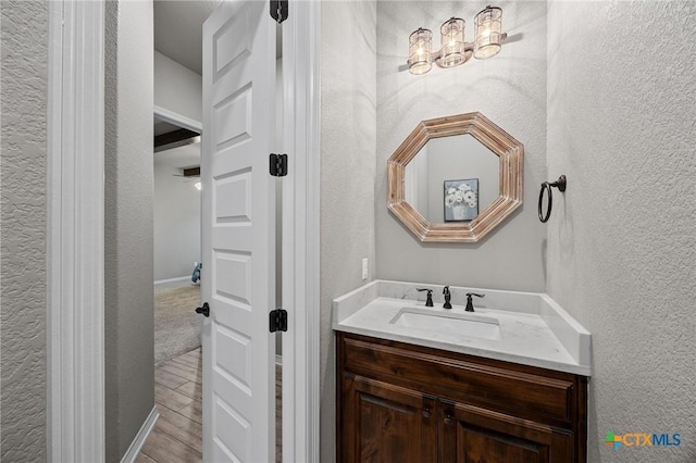 bathroom with vanity, wood finished floors, and a textured wall