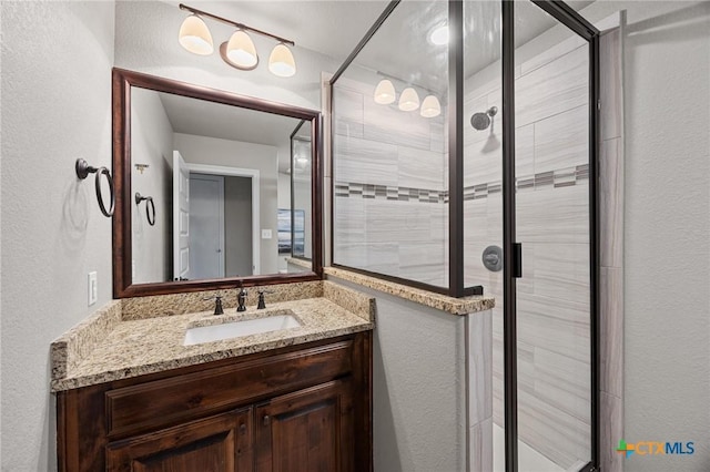 bathroom with vanity, a textured wall, and a stall shower