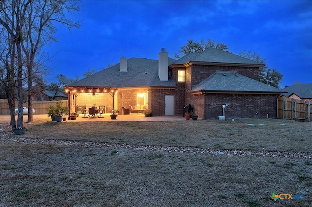 back of property with a ceiling fan, a patio, fence, brick siding, and a chimney