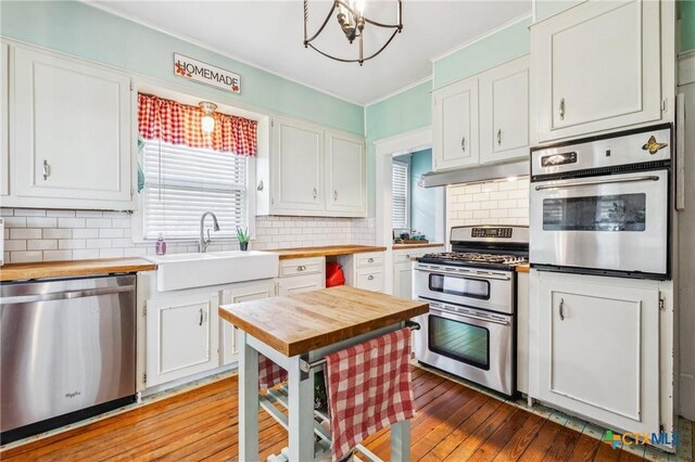 1004 Mitchell St, Gonzales, TX 78629 - kitchen featuring wood counters, appliances with stainless steel finishes, plenty of natural light, white cabinetry, and crown molding