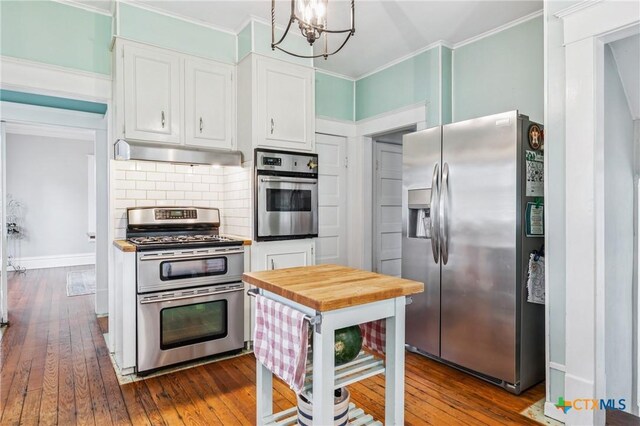 1004 Mitchell St, Gonzales, TX 78629 - kitchen featuring stainless steel appliances, under cabinet range hood, white cabinets, dark wood-type flooring, and backsplash