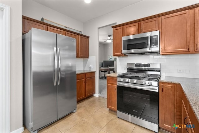 11602 Buster Crabbe Dr, Austin, TX 78748 - kitchen featuring stainless steel appliances, brown cabinetry, tasteful backsplash, and light stone counters