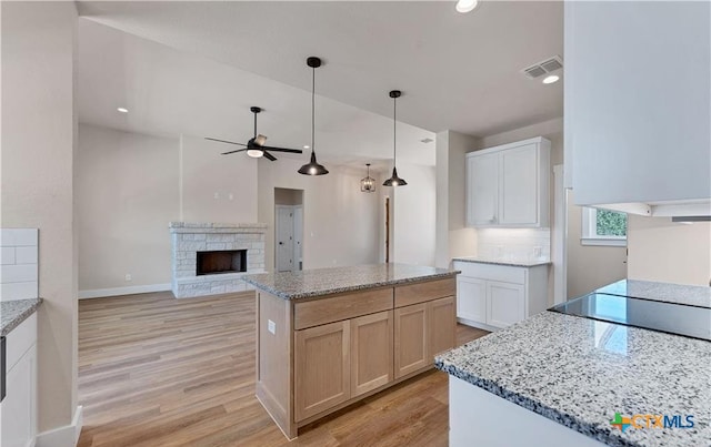 1435 Redwood Rd, Fischer, TX 78623 - kitchen with a stone fireplace, a ceiling fan, light wood-type flooring, light stone countertops, and recessed lighting
