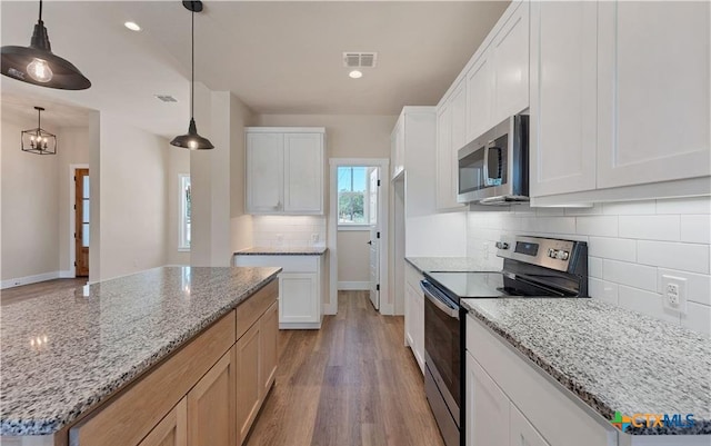 1435 Redwood Rd, Fischer, TX 78623 - kitchen with appliances with stainless steel finishes, wood finished floors, decorative backsplash, white cabinets, and recessed lighting