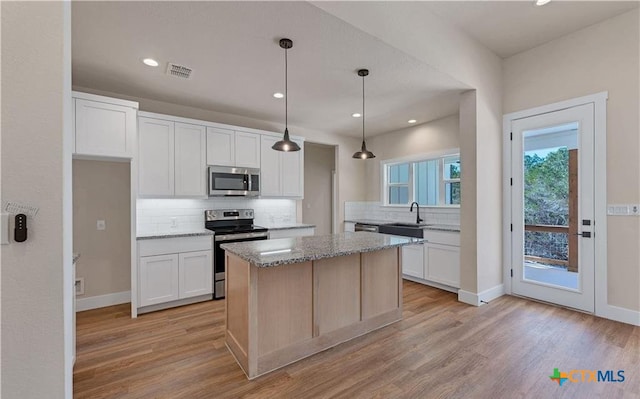 1435 Redwood Rd, Fischer, TX 78623 - kitchen featuring stainless steel appliances, a sink, backsplash, light stone counters, and light wood-style flooring