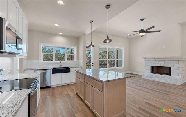 1435 Redwood Rd, Fischer, TX 78623 - kitchen with stainless steel appliances, a sink, ceiling fan, light wood-style flooring, and decorative backsplash