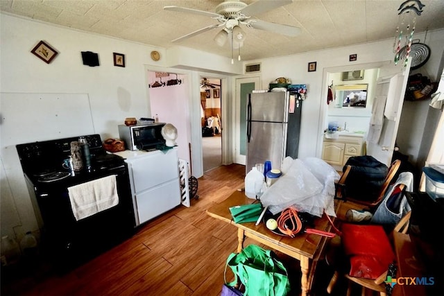 415 S 15th St, Port Oconnor, TX 77982 - kitchen featuring wood finished floors, freestanding refrigerator, range with electric cooktop, ceiling fan, and visible vents