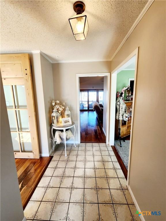 corridor with ornamental molding and a textured ceiling