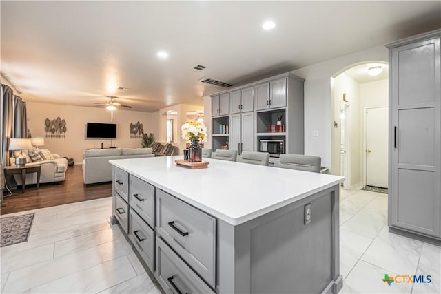 kitchen featuring gray cabinets, a center island, and ceiling fan