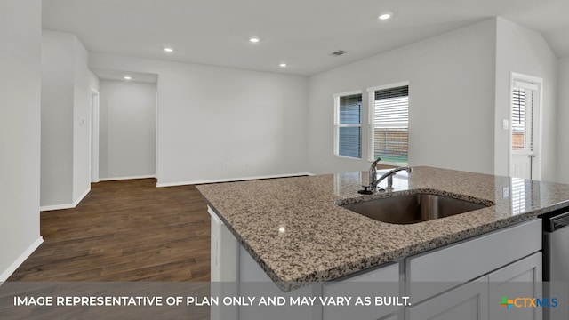 kitchen with light stone countertops, sink, an island with sink, and dark wood-type flooring