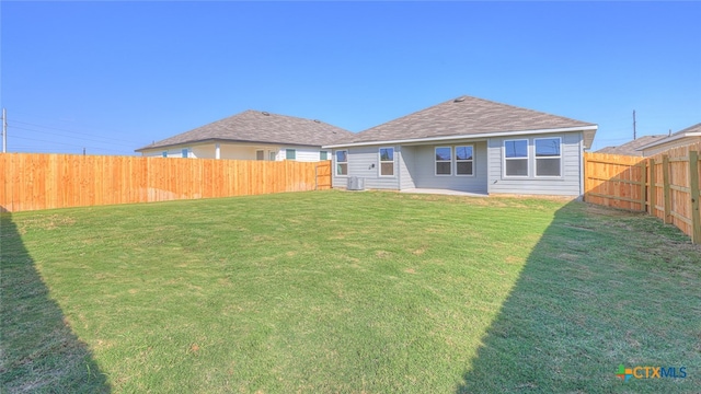 rear view of house featuring central AC and a lawn