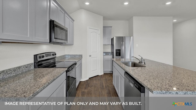 kitchen with dark wood-type flooring, a center island with sink, sink, light stone countertops, and appliances with stainless steel finishes