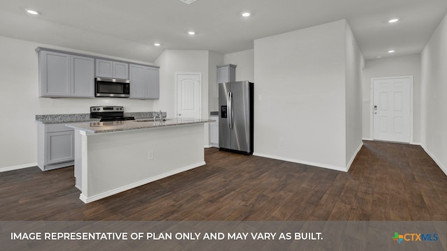 kitchen featuring gray cabinetry, light stone countertops, stainless steel appliances, dark hardwood / wood-style floors, and a kitchen island with sink