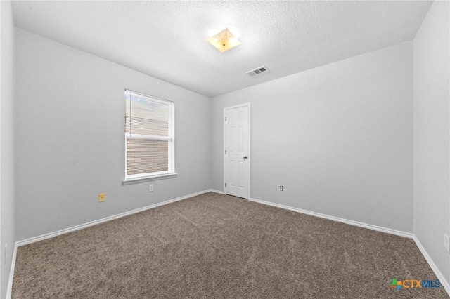 unfurnished room with carpet flooring and a textured ceiling