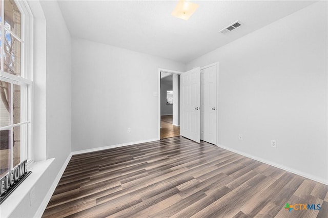 empty room featuring dark hardwood / wood-style flooring and a healthy amount of sunlight