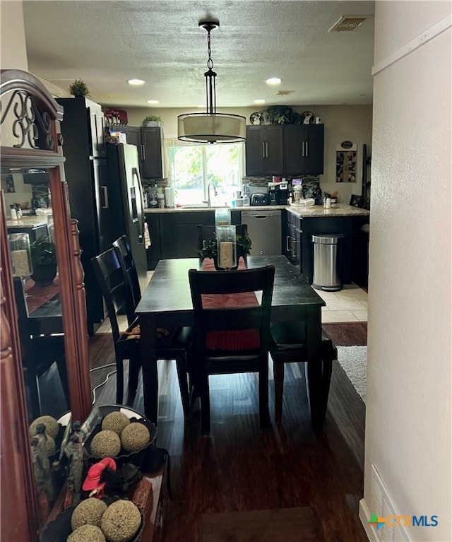 dining area featuring light hardwood / wood-style floors, a textured ceiling, and sink