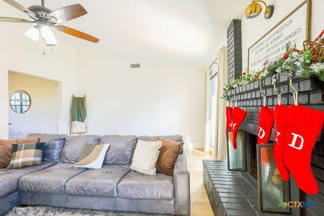 living room with ceiling fan, a brick fireplace, and hardwood / wood-style floors