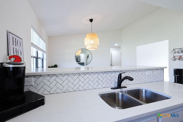 kitchen featuring light stone counters, sink, pendant lighting, and tasteful backsplash