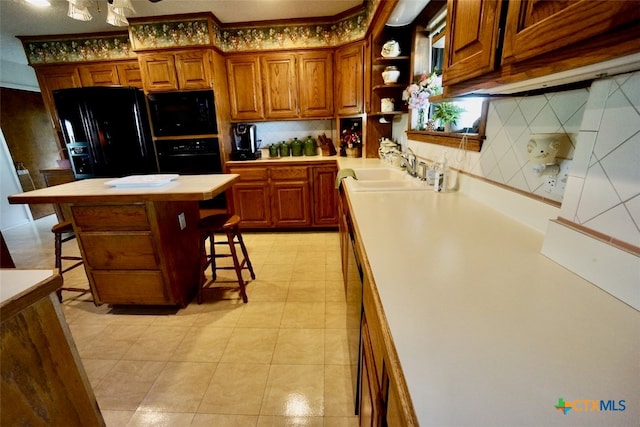 kitchen with black appliances, decorative backsplash, sink, a breakfast bar area, and a center island