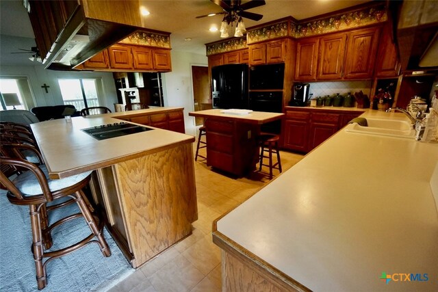 kitchen featuring a center island, kitchen peninsula, black appliances, a breakfast bar area, and sink