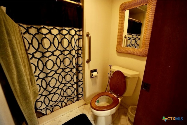 bathroom featuring tile patterned flooring, curtained shower, and toilet