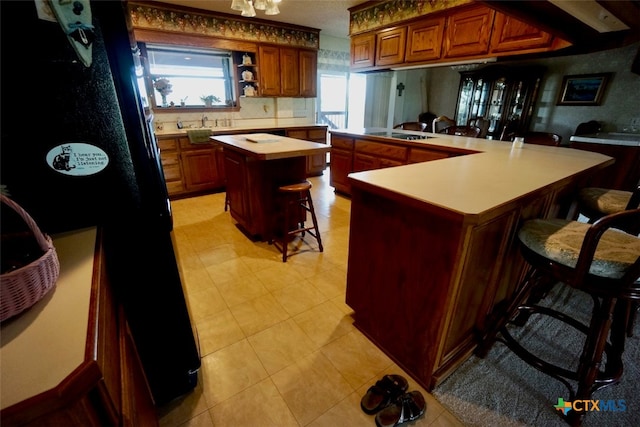 kitchen with black fridge, decorative backsplash, a breakfast bar area, a kitchen island, and stovetop