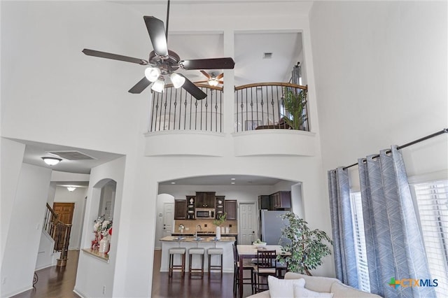 2474 Santa Barbara Loop, Round Rock, TX 78665 - living room featuring a high ceiling, a ceiling fan, dark wood-style flooring, stairway, and arched walkways