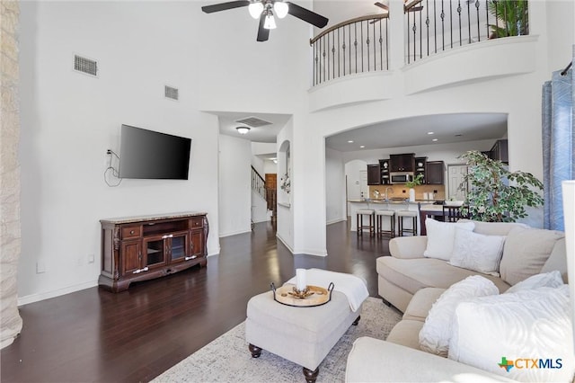 2474 Santa Barbara Loop, Round Rock, TX 78665 - living room featuring dark wood finished floors, a ceiling fan, a towering ceiling, arched walkways, and baseboards
