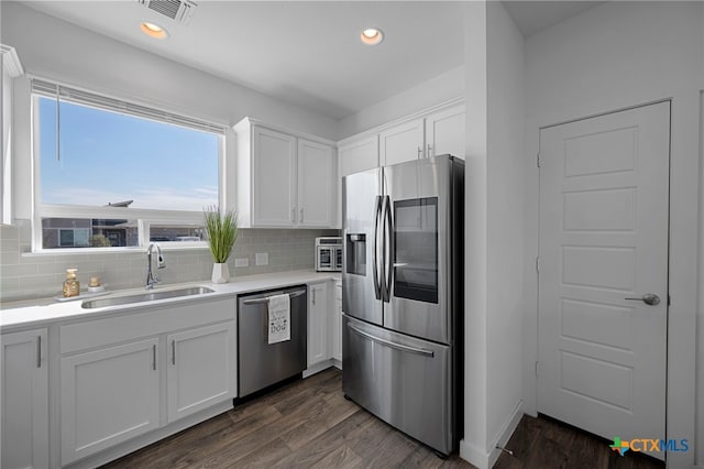 kitchen featuring dark wood-style flooring, stainless steel appliances, tasteful backsplash, white cabinetry, and a sink