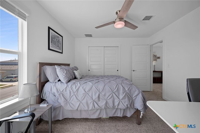 carpeted bedroom with a closet, visible vents, and multiple windows