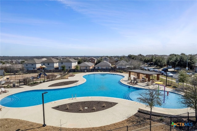 community pool featuring a patio area, fence, and a residential view