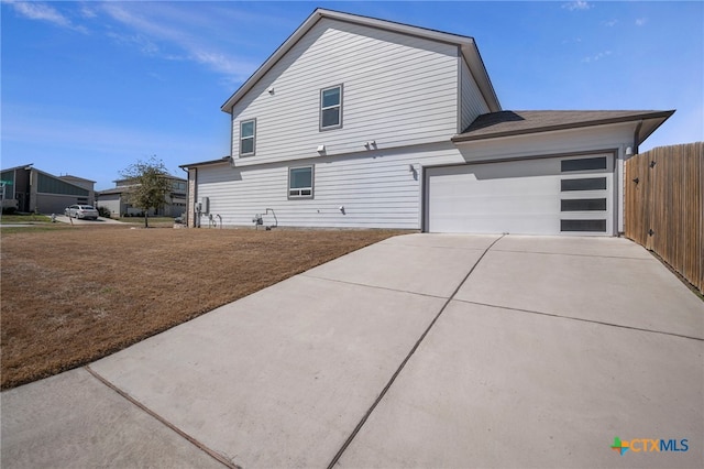 exterior space with a garage, concrete driveway, and fence