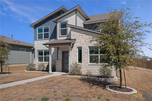 view of front of property with stone siding, board and batten siding, and fence