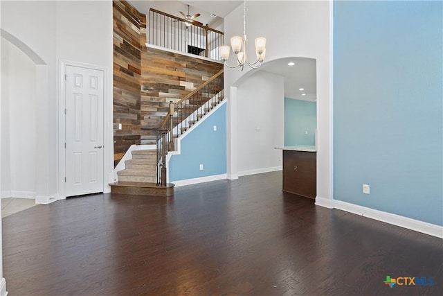 empty room with dark hardwood / wood-style floors, a high ceiling, and a notable chandelier