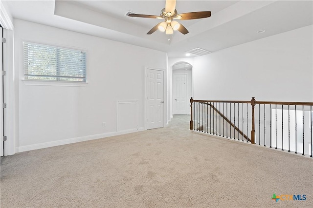 carpeted empty room featuring ceiling fan and a tray ceiling