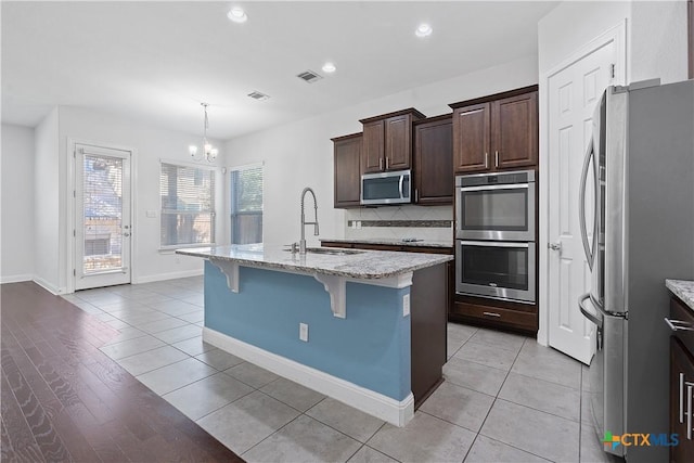 kitchen with sink, stainless steel appliances, backsplash, a kitchen bar, and a kitchen island with sink